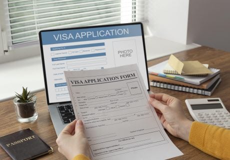 Documentos y pantalla digital mostrando el proceso de tramitación online para la extensión de la visa de estudiante en Australia.