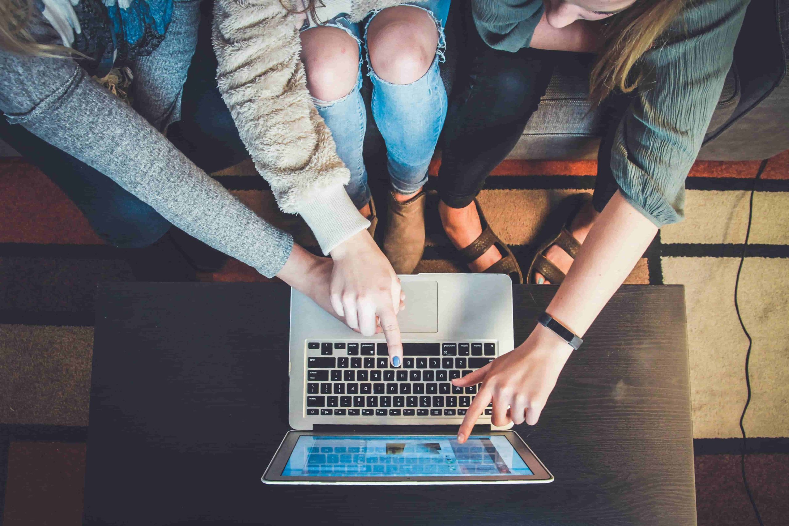 Three girls reviewing a resume on a laptop to work in Australia