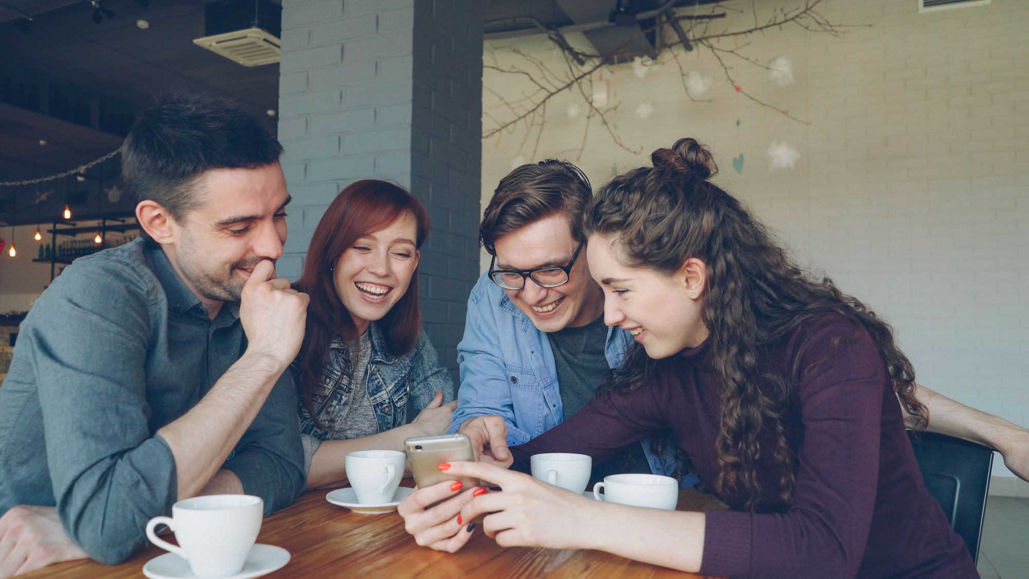 Amigos compartiendo un café y mirando un teléfono
