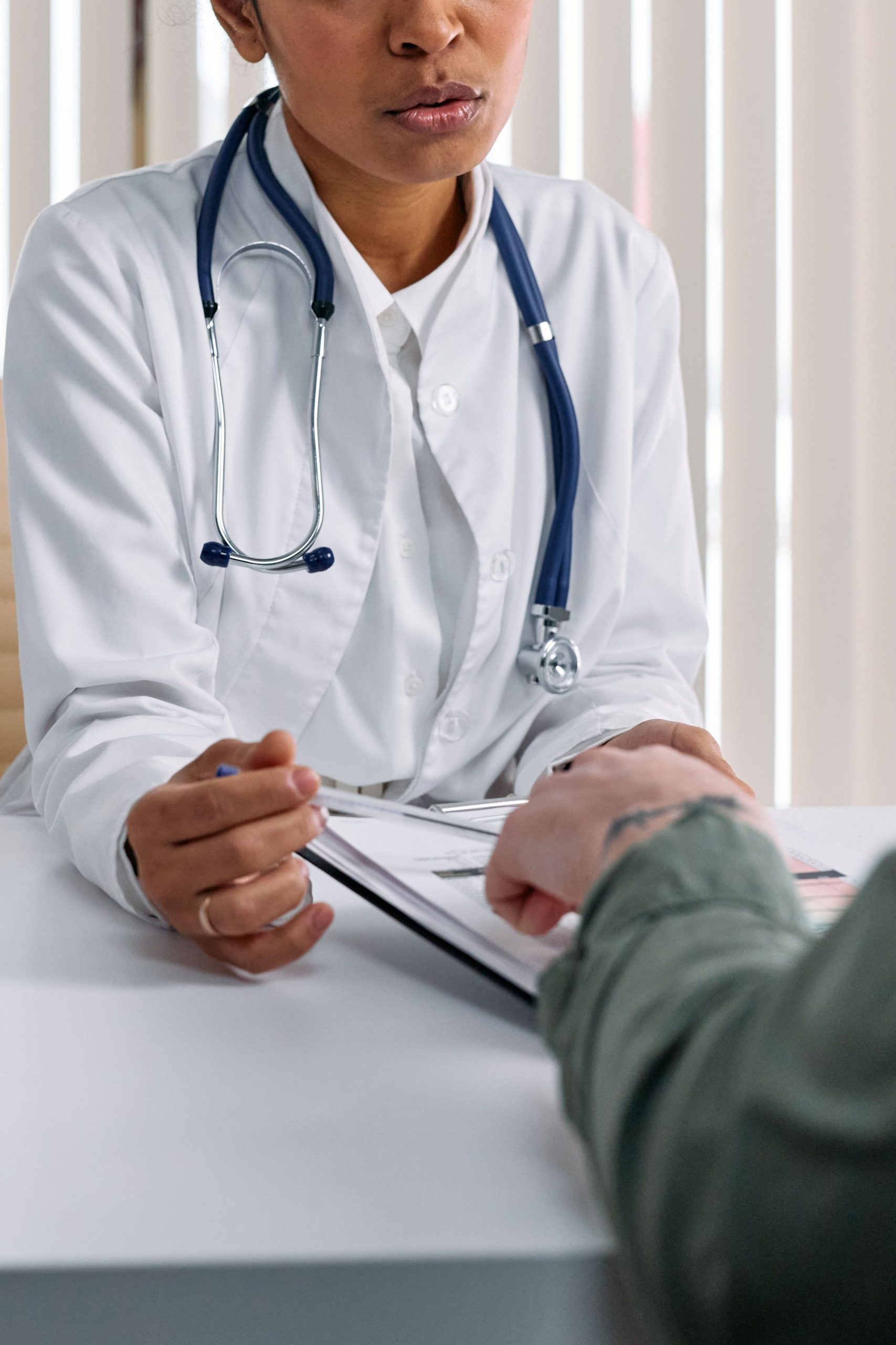 Profesional de la salud revisando documentos con una persona en consulta.