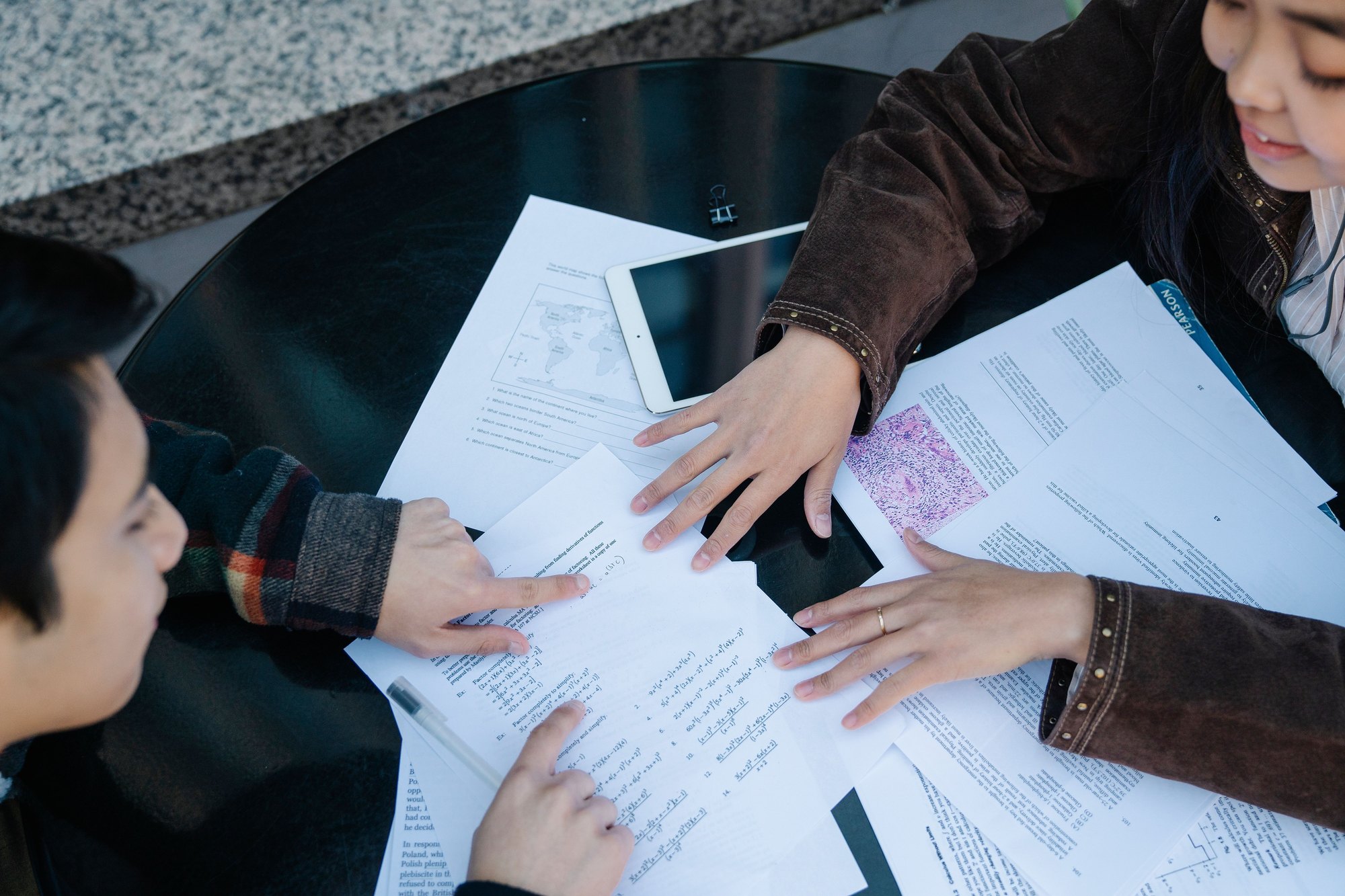 Dos estudiantes revisando apuntes y documentos en una mesa.