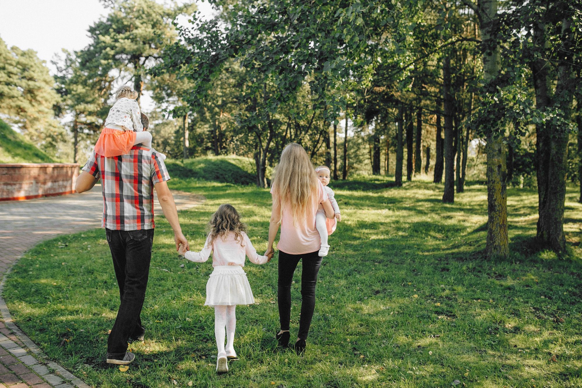 Familia con tres hijos paseando por un parque arbolado