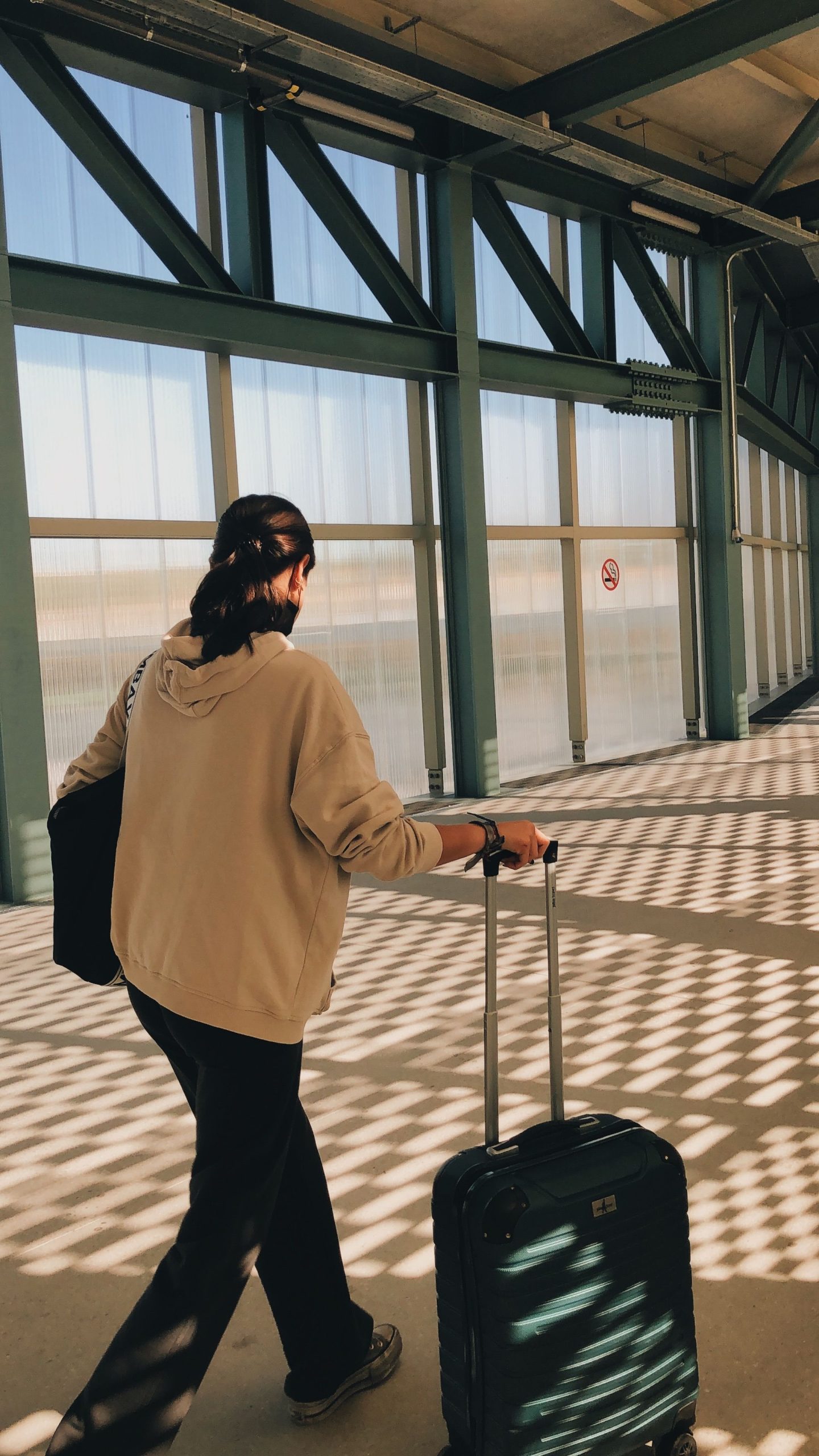 Viajera caminando con una maleta por la terminal de un aeropuerto