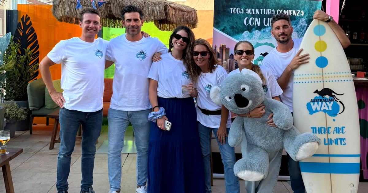 Equipo de Australian Way con camisetas de la agencia, una tabla de surf y un koala de peluche en un evento en Madrid
