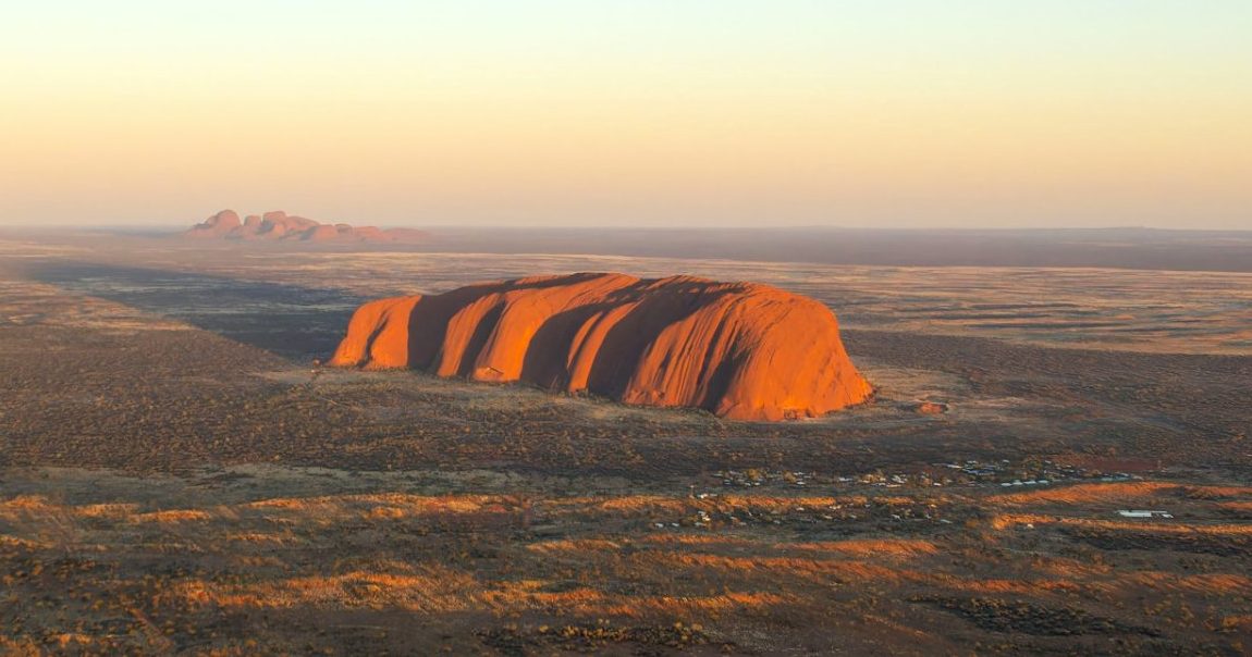 Vista aérea de Uluru al atardecer en el centro rojo de Australia, con Kata Tjuta al fondo